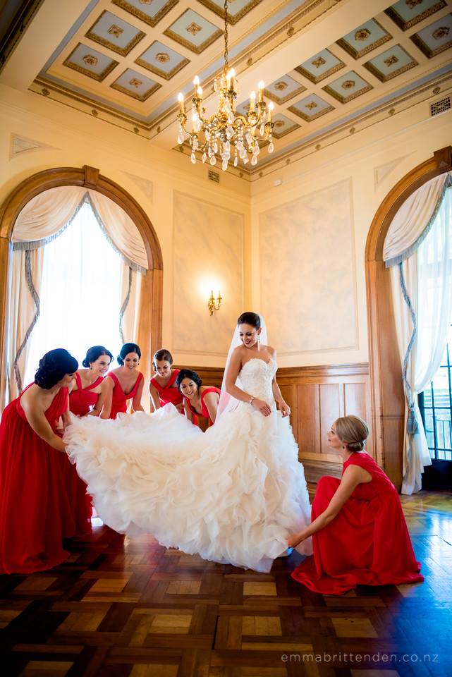 The bridesmaids are helping the bride holding the gown