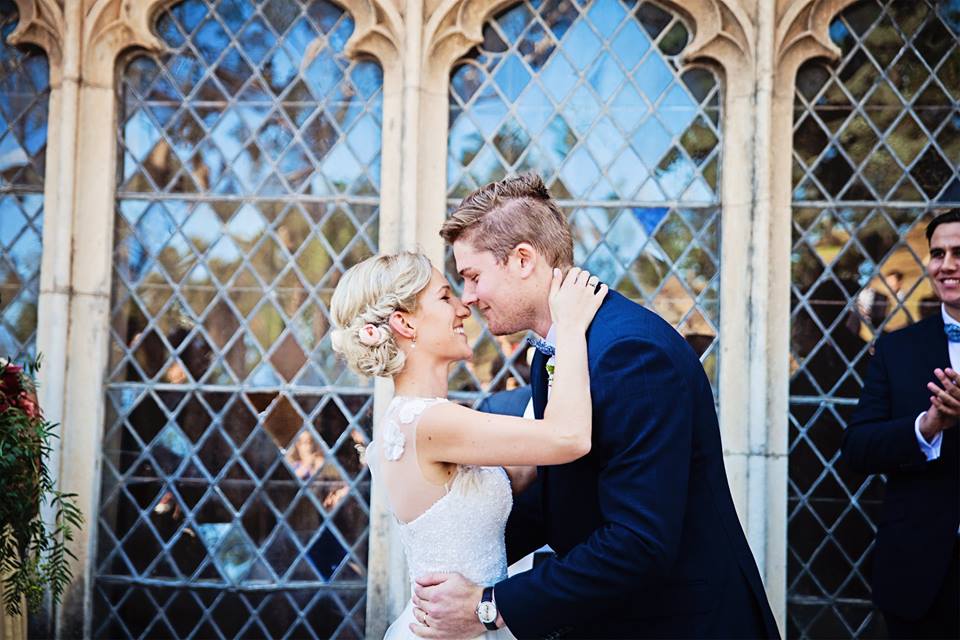 A couple kissing with rustic window at the backdrop at Montsalvat