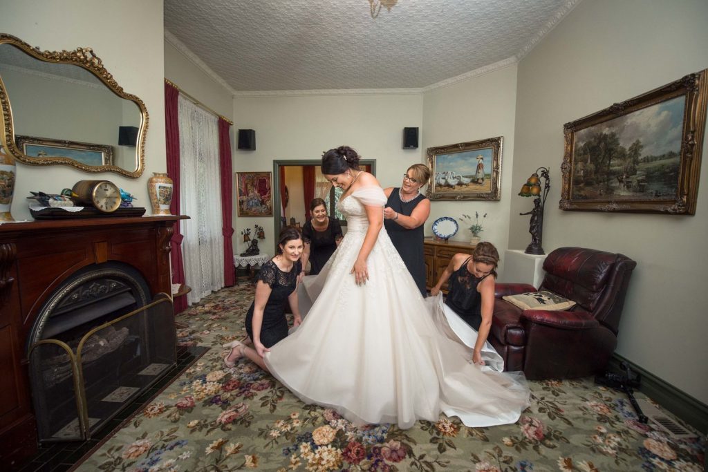 A bride in her vintage bride room at Wild Cattle Creek and some women helped her to tidy up her gown