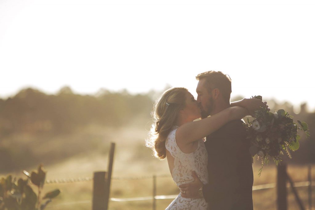 A wedding couple kissing with vineyards of Bianchet Bistro and Winery as a backdrop