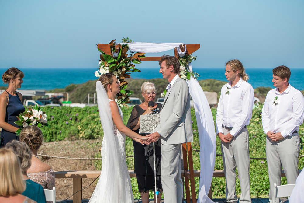 A wedding vow exchange with ocean as the background