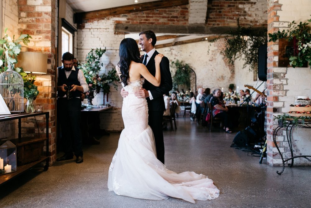 A wedding couple dancing in a rustic room with bricks