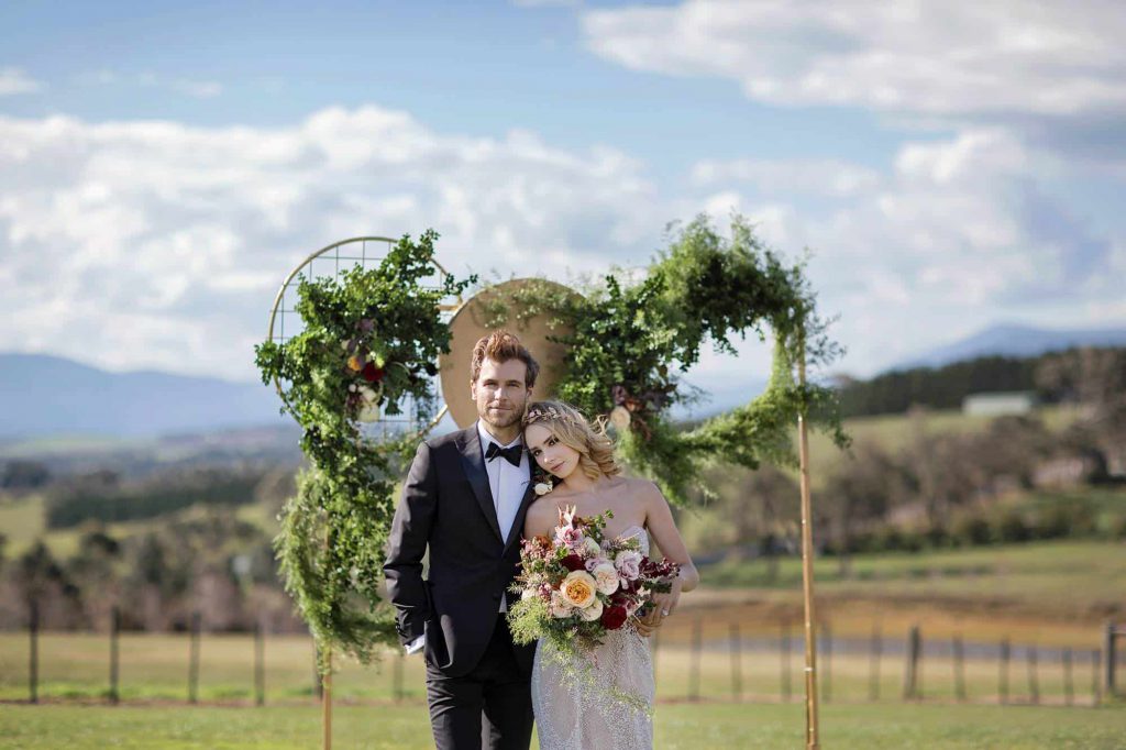 A wedding couple posing with vineyards at Vines at The Yarra Valley as a backdrop