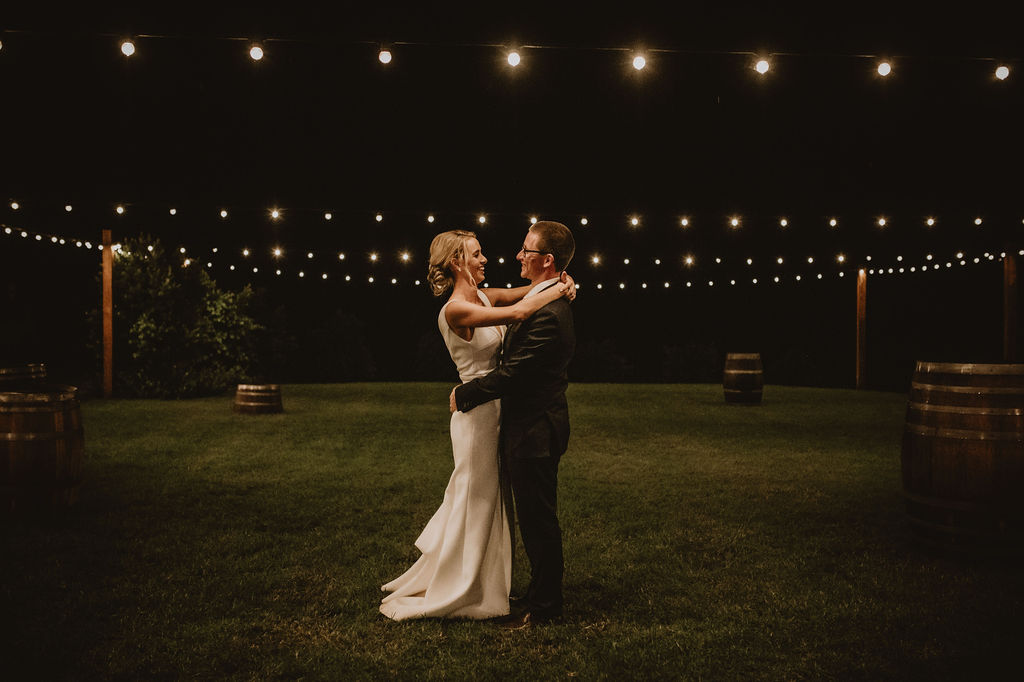 A couple is dancing on the courtyard under the fairy lights