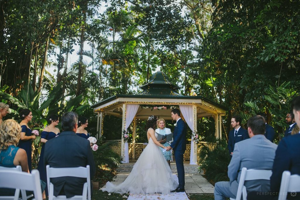 A wedding vow exchange with garden gazebo as the backdrop