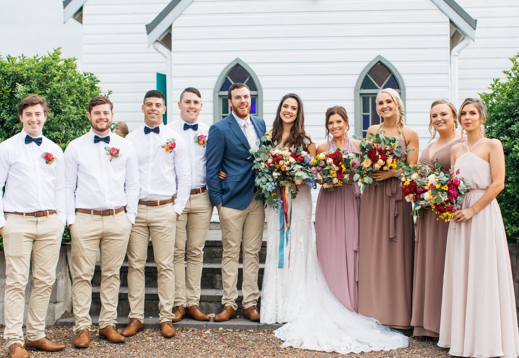 Wedding couple, bridesmaids, and groomsmen in front of the chapel