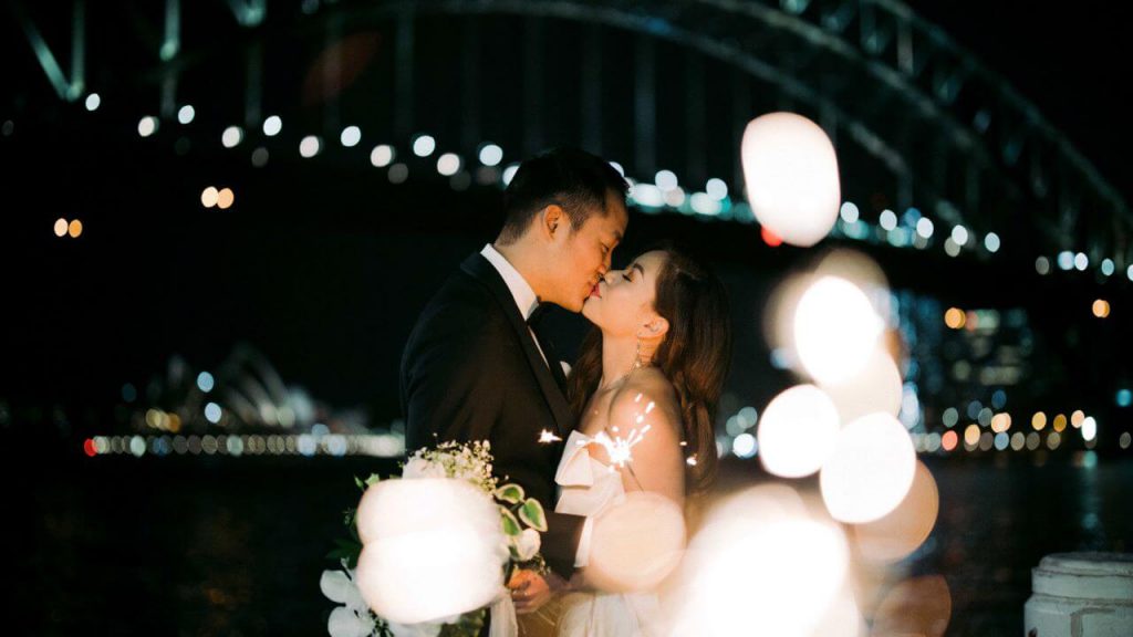 A wedding couple kissing with Sydney bridge as the backdrop