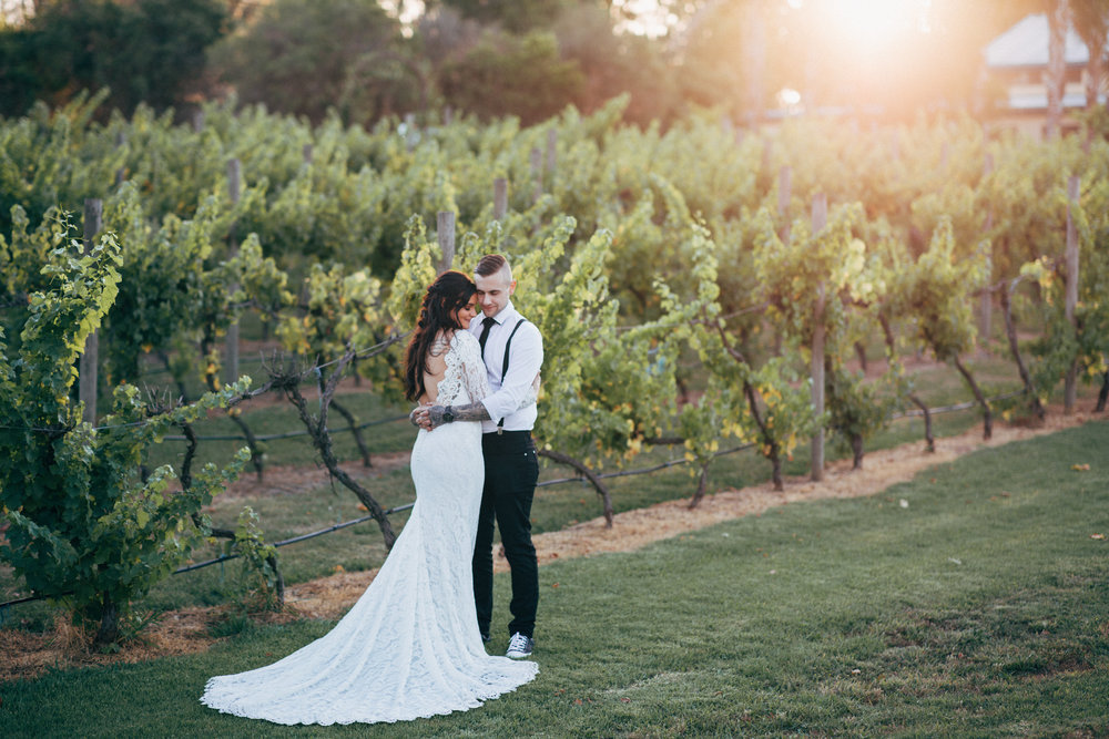 A wedding couple hugging with vineyards at the background