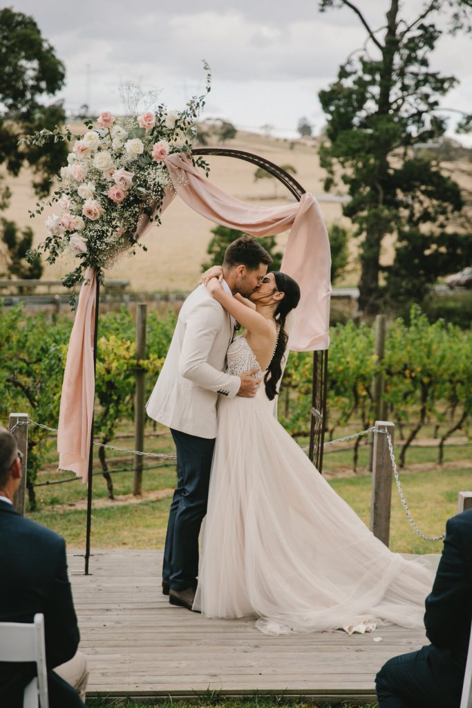 A couple is kissing with vineyards as the backdrop