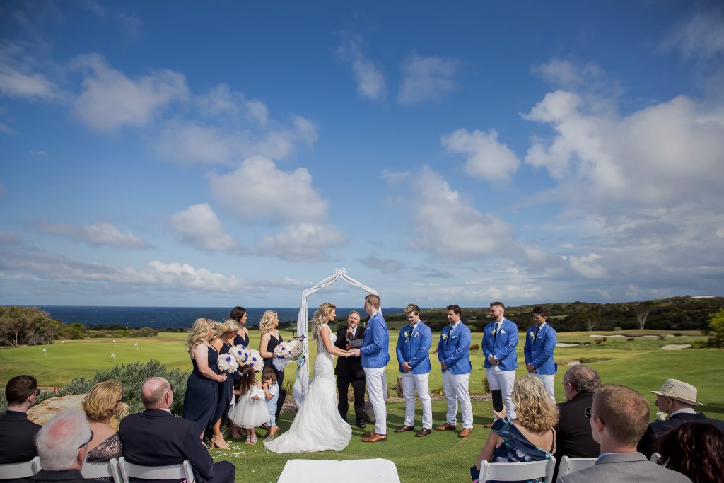 Exchanging wedding vows on a courtyard with ocean as a backdrop